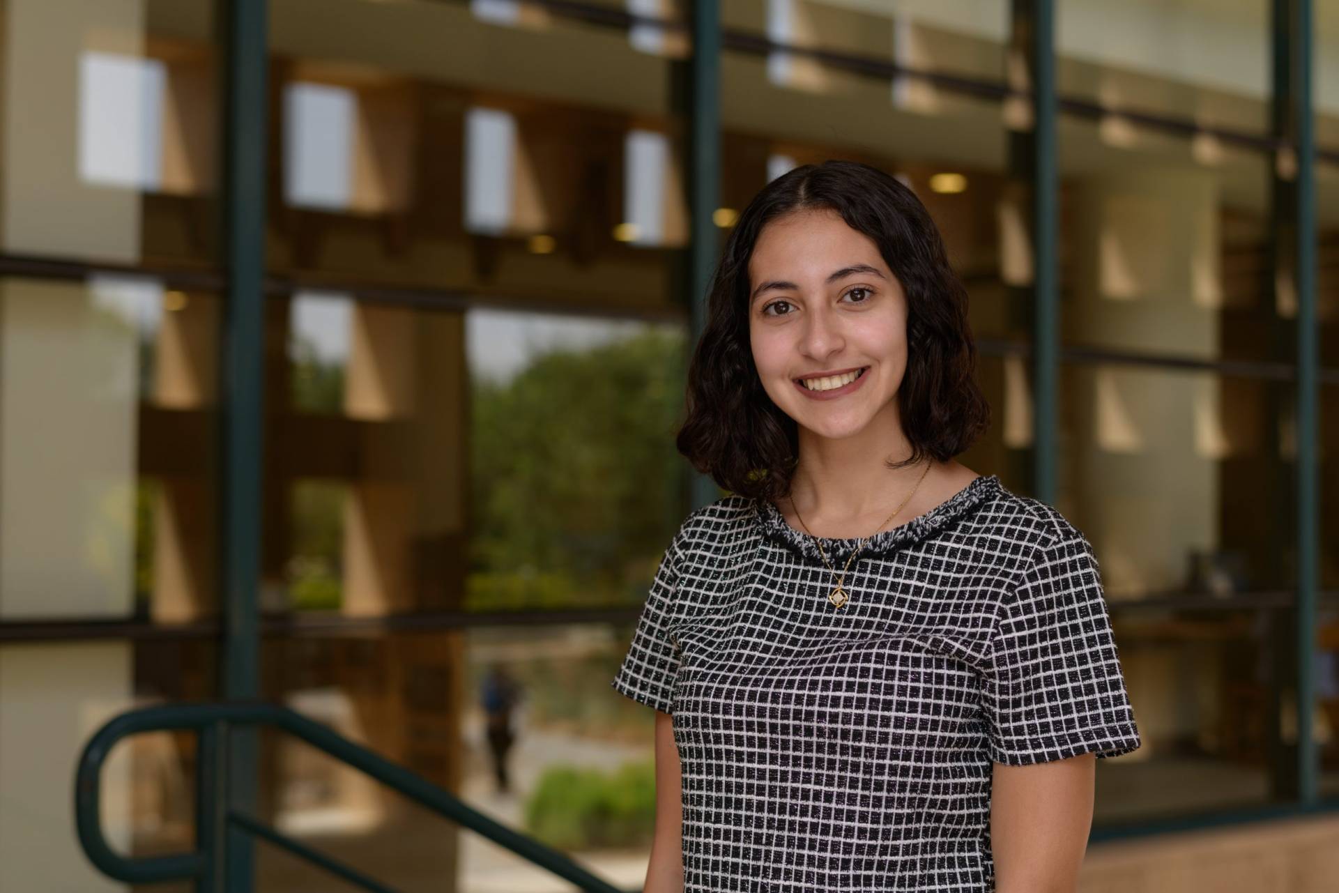 One female student smiling standing outside.