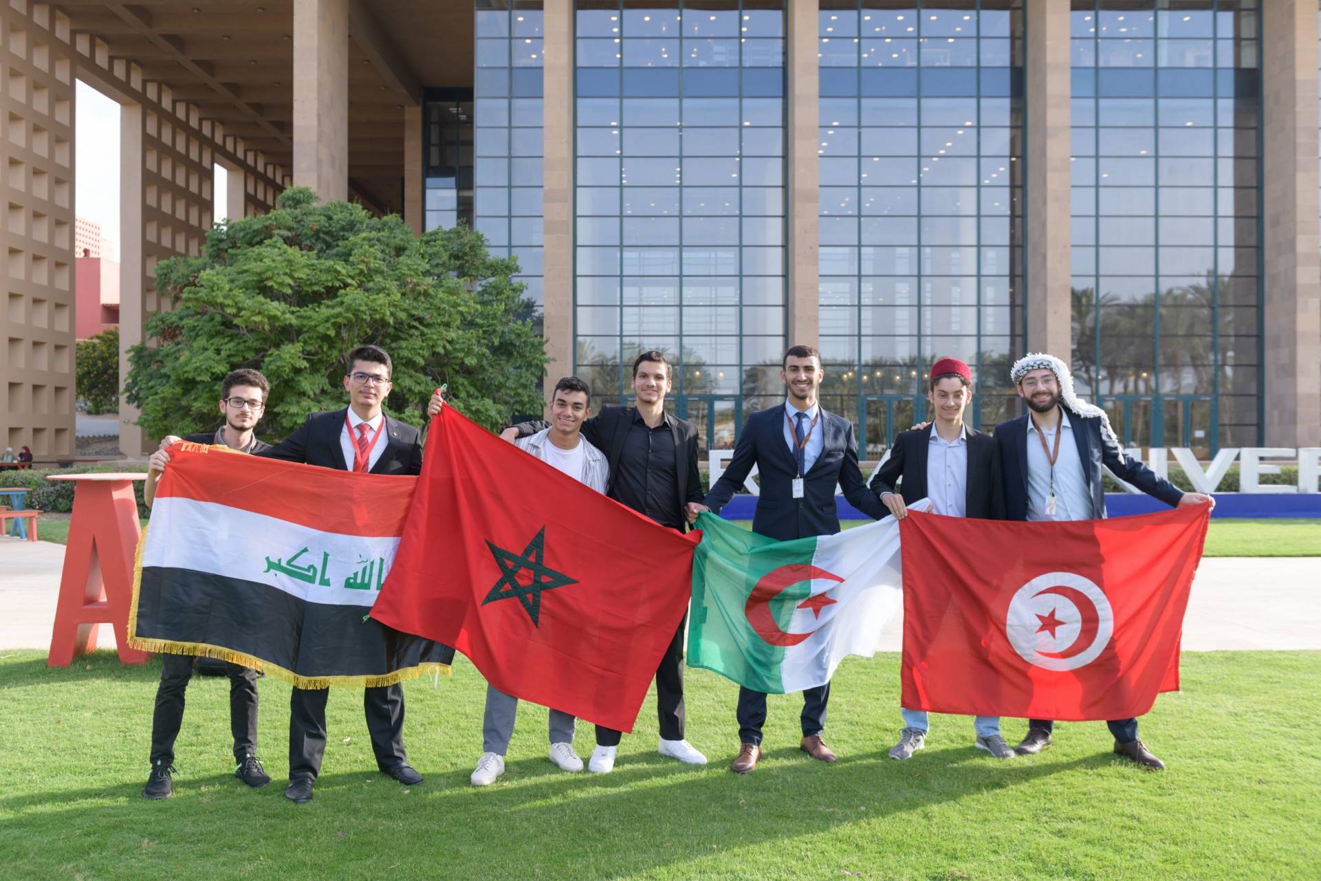 Group of seven male students holding country flags.