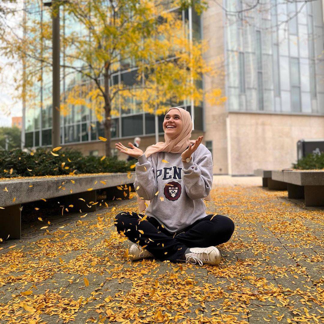 One female student smiling standing outside.